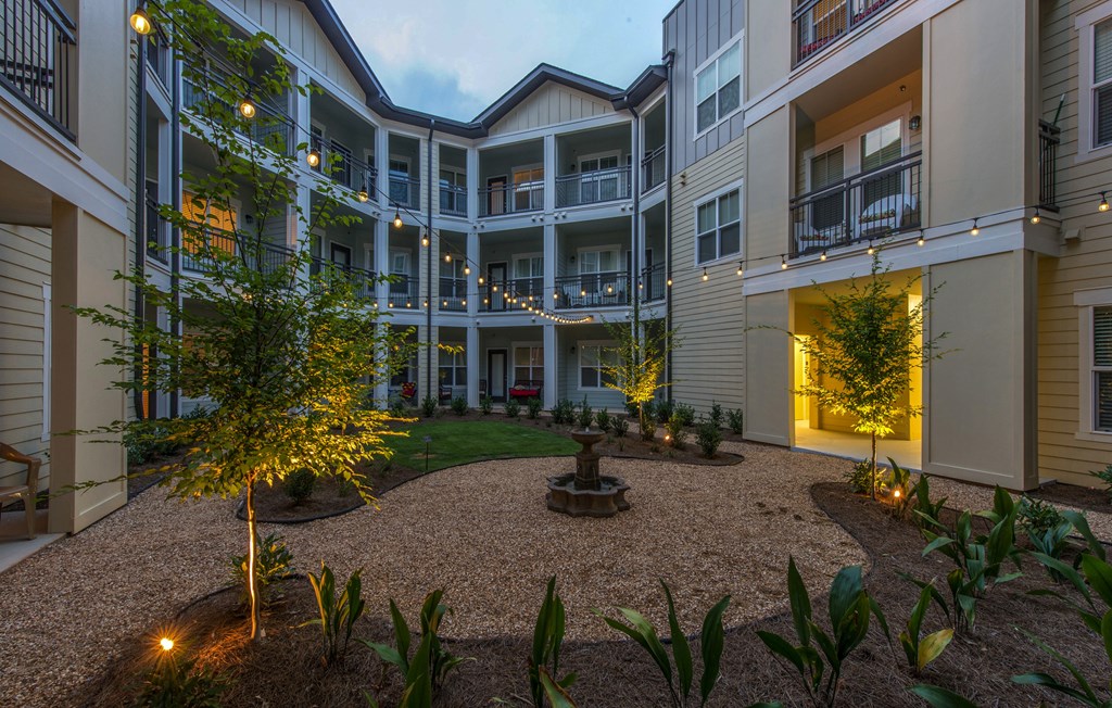 A courtyard with a tree and plants in front of apartment buildings.